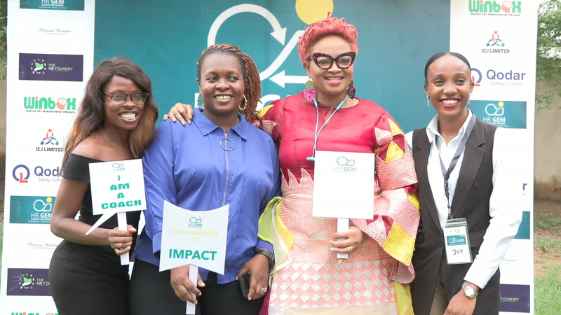 Members holding "I am a coach" and "Impact" placards at the May Day hangout