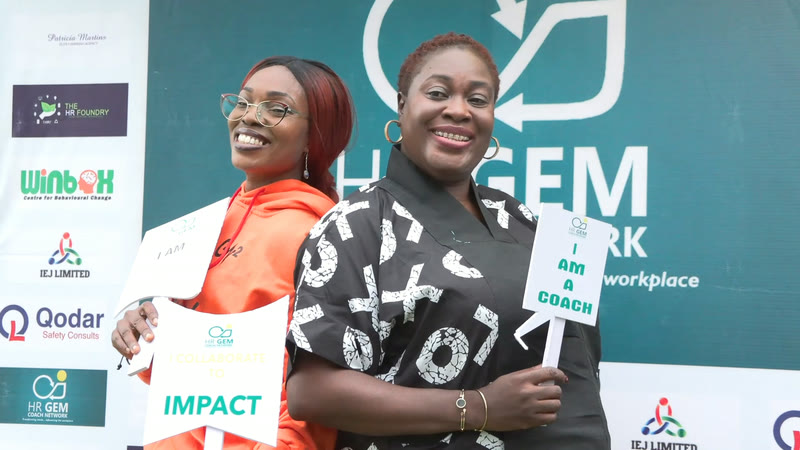 Two smiling members holding "I am a coach" placards