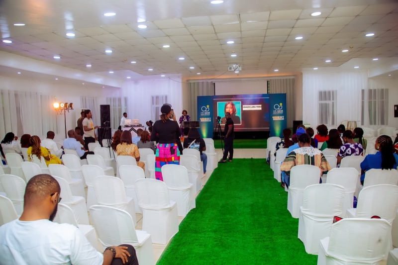 The event hall with rows of white chairs along a green carpet