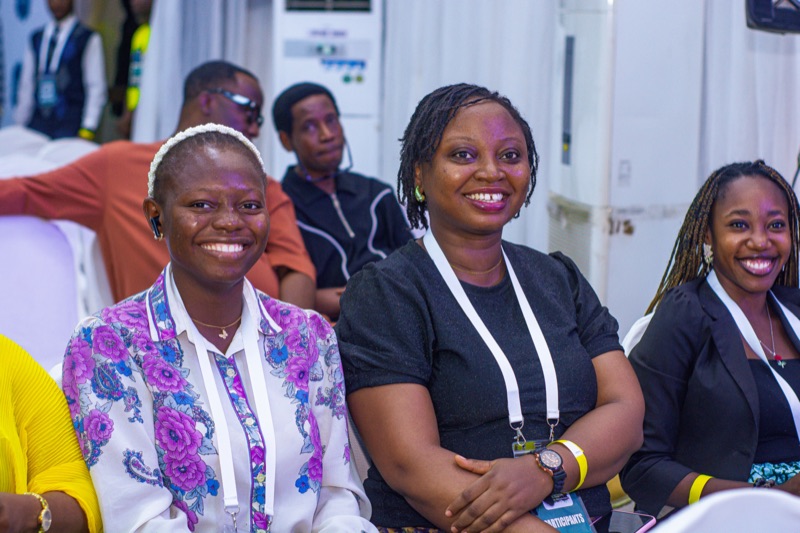 Three smiling attendees seated in the audience