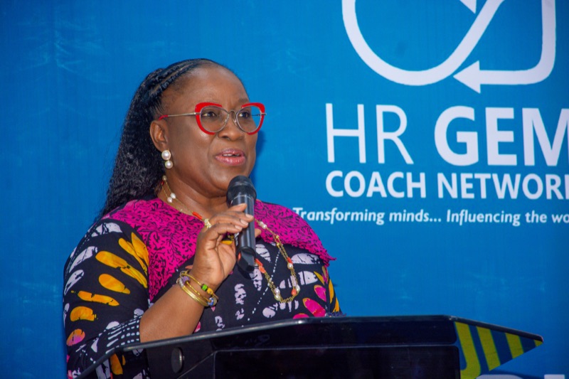 A speaker addressing the audience from the podium in front of the HR GEM Coach Network backdrop