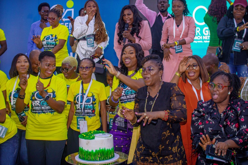 Attendees in yellow T-shirts cheering around a celebration cake